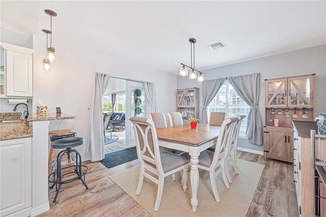 dining area featuring plenty of natural light, sink, and light hardwood / wood-style flooring