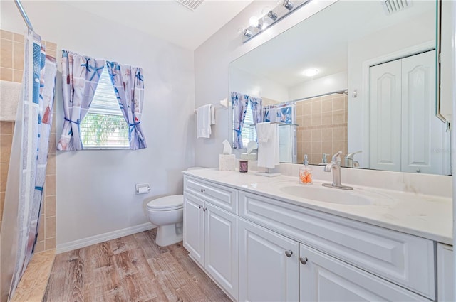 bathroom with hardwood / wood-style flooring, vanity, toilet, and walk in shower