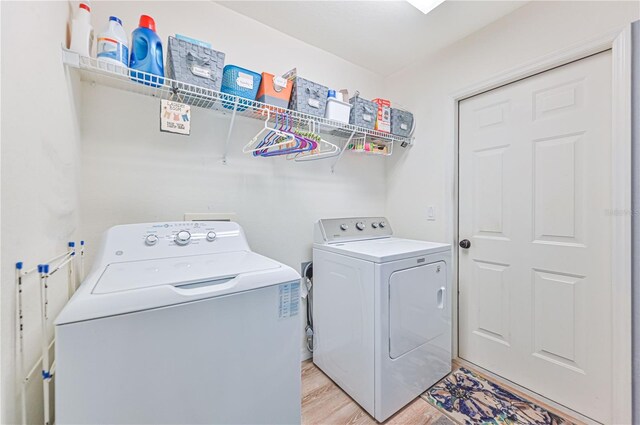 laundry room featuring independent washer and dryer and light hardwood / wood-style floors