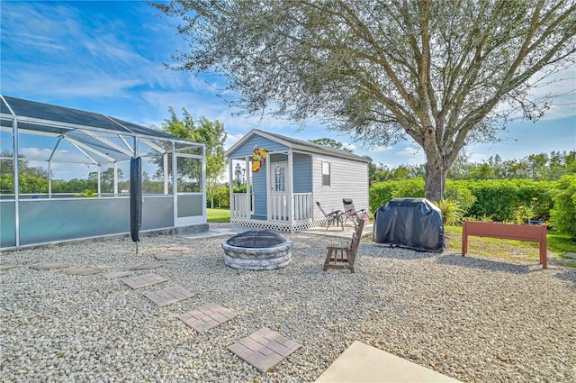 rear view of property with an outbuilding, a lanai, and an outdoor fire pit