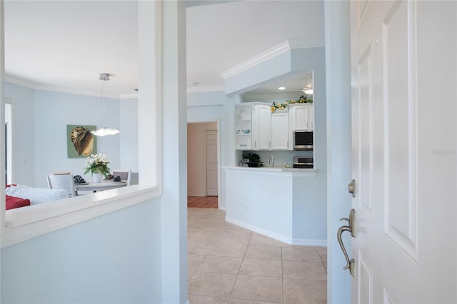 interior space with light tile patterned flooring, white cabinetry, crown molding, pendant lighting, and stove