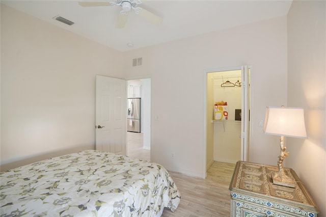 bedroom with ceiling fan, light hardwood / wood-style floors, and stainless steel fridge with ice dispenser