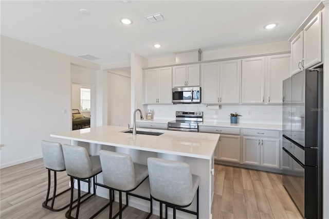 kitchen with stainless steel appliances, an island with sink, sink, and a breakfast bar