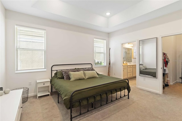 carpeted bedroom featuring ensuite bathroom, a spacious closet, and a raised ceiling