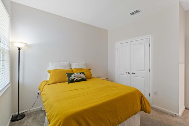 bedroom with multiple windows, light colored carpet, and a closet