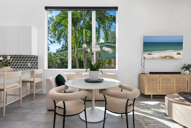 dining room featuring a water view, a healthy amount of sunlight, and a view of the beach