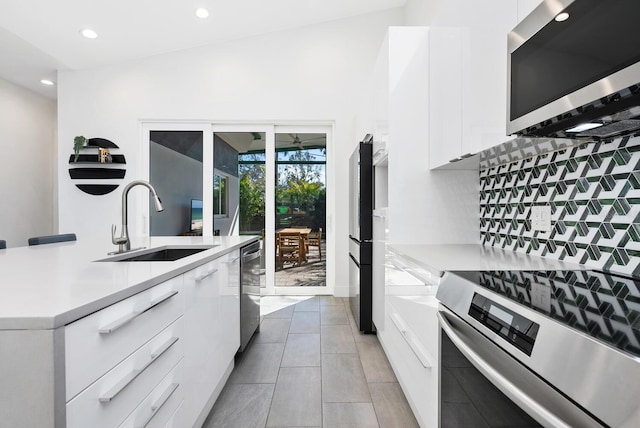 kitchen featuring stainless steel appliances, sink, white cabinets, and backsplash