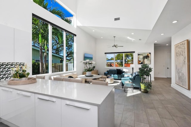 kitchen featuring ceiling fan, a high ceiling, and white cabinets