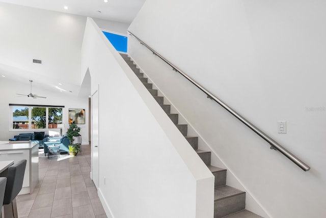 staircase featuring tile patterned flooring, a towering ceiling, and ceiling fan