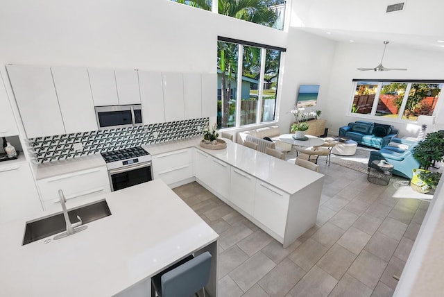 kitchen featuring a towering ceiling, wall oven, a wealth of natural light, and white cabinets