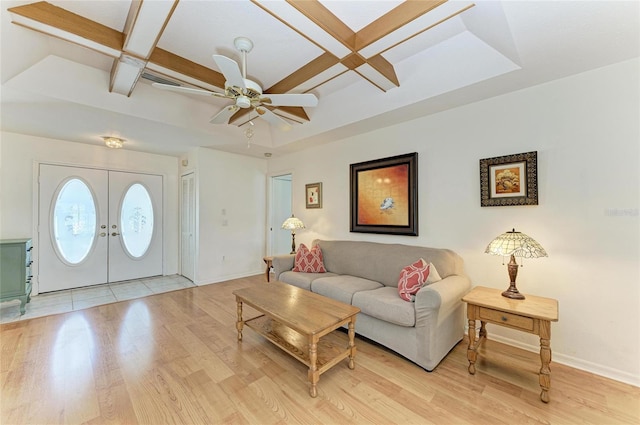 living room with french doors, coffered ceiling, light hardwood / wood-style flooring, beamed ceiling, and ceiling fan