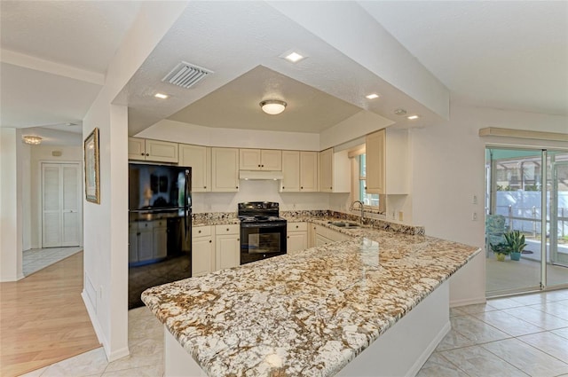 kitchen featuring sink, kitchen peninsula, light stone counters, and black appliances