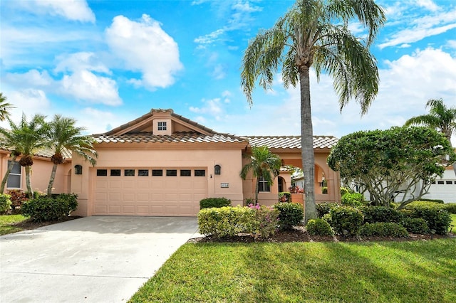 mediterranean / spanish house with a tile roof, stucco siding, a front yard, a garage, and driveway