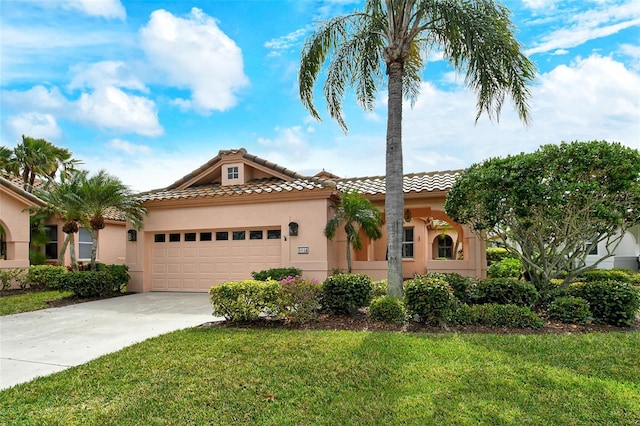 mediterranean / spanish home featuring an attached garage, driveway, a tiled roof, stucco siding, and a front yard