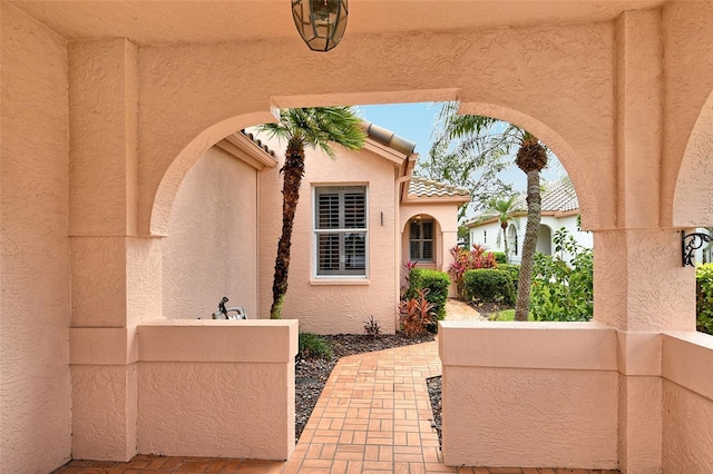 entrance to property with a tile roof and stucco siding