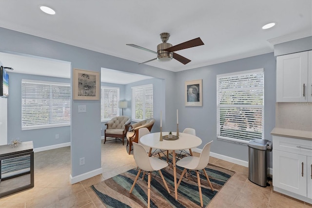 tiled dining space featuring ceiling fan, ornamental molding, and plenty of natural light