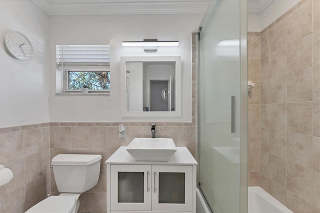 full bathroom featuring tile walls, vanity, bath / shower combo with glass door, and toilet