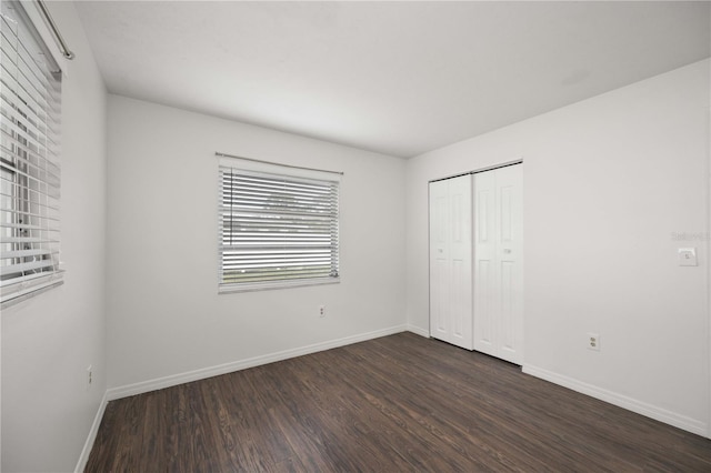 unfurnished bedroom featuring dark hardwood / wood-style flooring and a closet