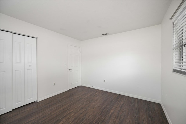 unfurnished bedroom with dark hardwood / wood-style floors and a closet