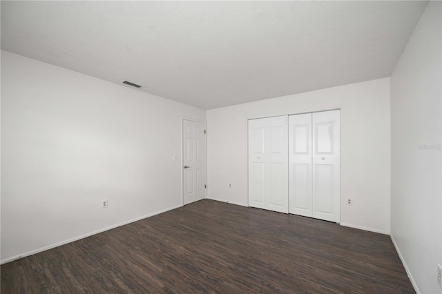 unfurnished bedroom featuring dark hardwood / wood-style flooring and a closet