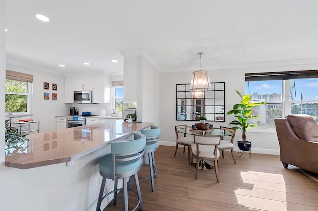 kitchen featuring stainless steel appliances, white cabinets, pendant lighting, a kitchen bar, and kitchen peninsula