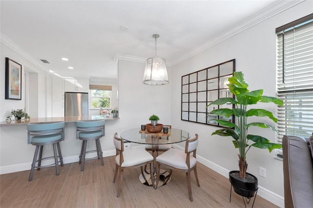 dining space featuring crown molding and light hardwood / wood-style floors