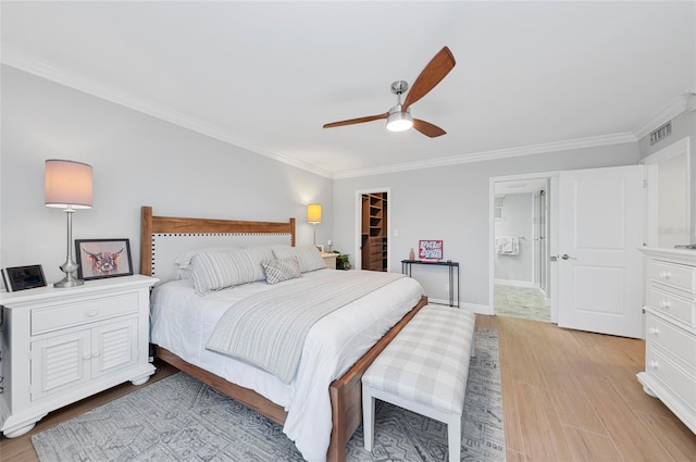 bedroom with ceiling fan, ornamental molding, a spacious closet, and light wood-type flooring