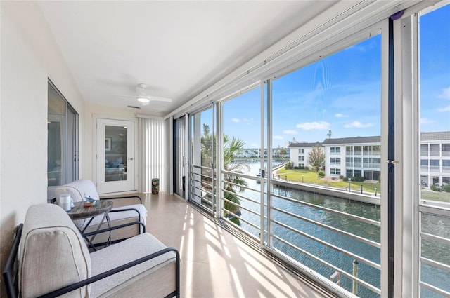 sunroom featuring a water view and ceiling fan