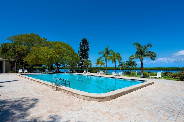 view of pool featuring a water view and a patio area