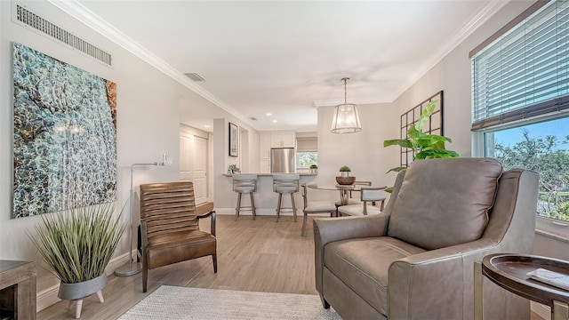 living area featuring baseboards, ornamental molding, visible vents, and light wood-style flooring