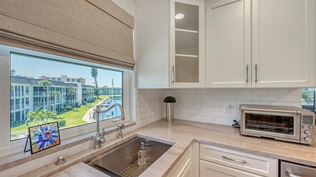 kitchen featuring white cabinets, backsplash, a toaster, and a sink
