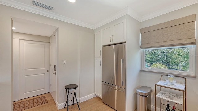 kitchen featuring white cabinets, visible vents, freestanding refrigerator, light wood-style floors, and baseboards