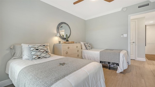 bedroom featuring baseboards, visible vents, light wood-style floors, a ceiling fan, and crown molding