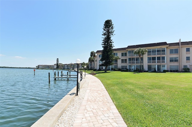 view of dock with a lawn and a water view