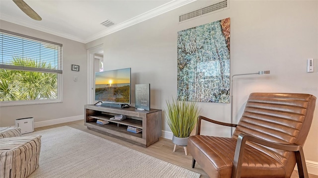 sitting room featuring baseboards, wood finished floors, visible vents, and crown molding