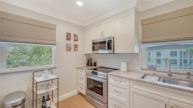 kitchen with light countertops, a sink, decorative backsplash, appliances with stainless steel finishes, and white cabinetry
