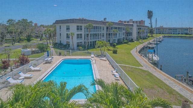 pool featuring a lawn, fence, a water view, and a patio area