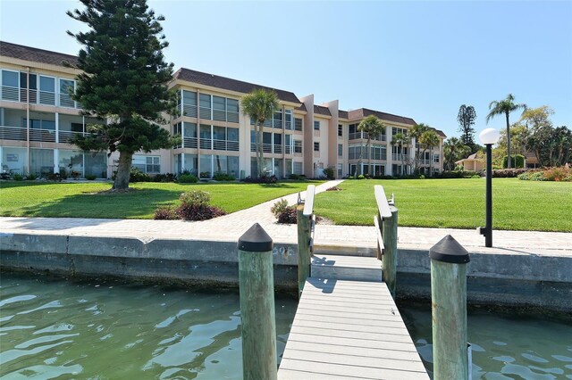 view of dock featuring a lawn and a water view