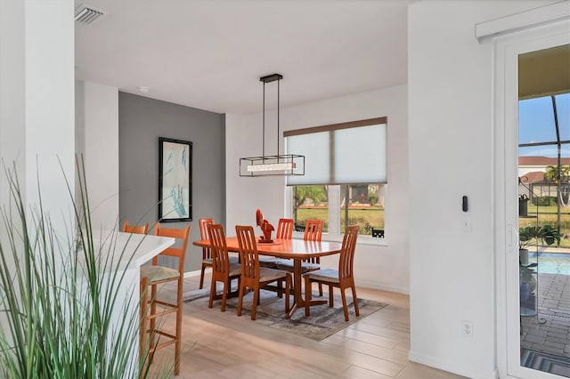 dining area with light hardwood / wood-style flooring, plenty of natural light, and a chandelier