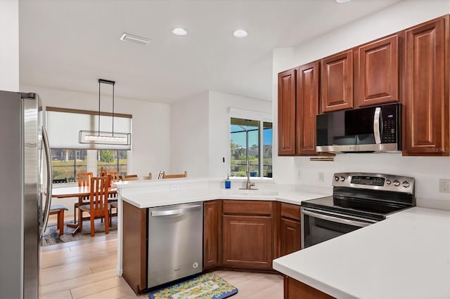 kitchen featuring stainless steel appliances, decorative light fixtures, sink, and kitchen peninsula