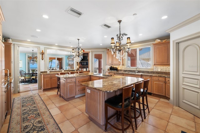 kitchen featuring a center island, visible vents, a kitchen bar, and an inviting chandelier