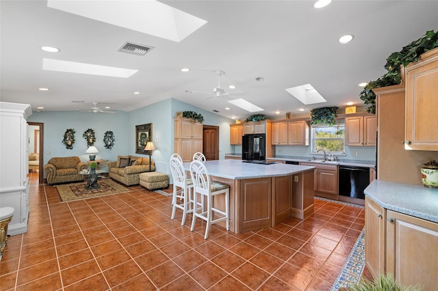 kitchen featuring tile patterned flooring, visible vents, a ceiling fan, black appliances, and a kitchen bar