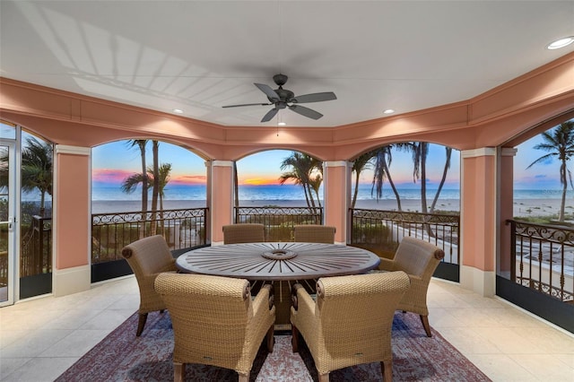 view of patio / terrace with a balcony, a water view, a view of the beach, and a ceiling fan