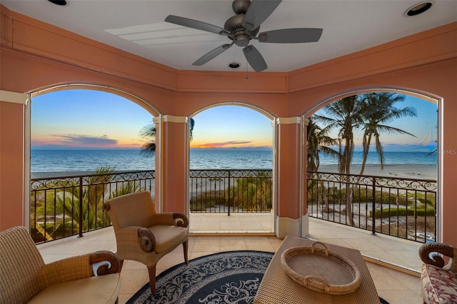 balcony with a water view, ceiling fan, and a beach view