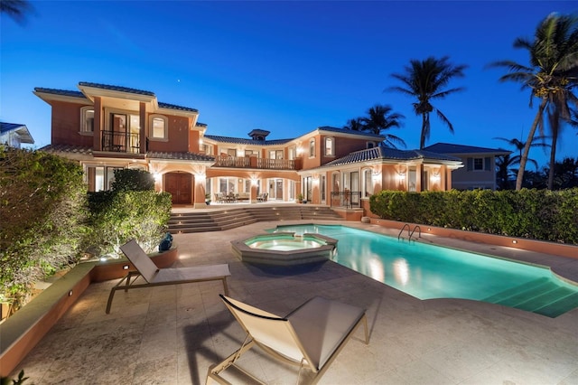 back of house featuring a pool with connected hot tub, a patio area, a tile roof, and a balcony