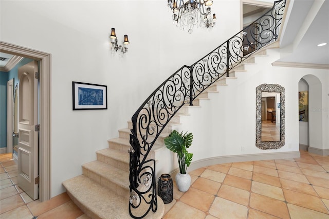 staircase with baseboards, arched walkways, crown molding, and tile patterned floors