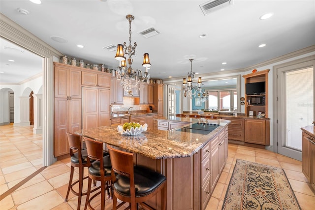 kitchen featuring arched walkways, a large island, visible vents, a chandelier, and black appliances