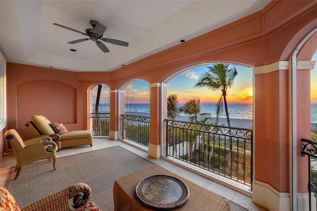 balcony at dusk with a water view and ceiling fan