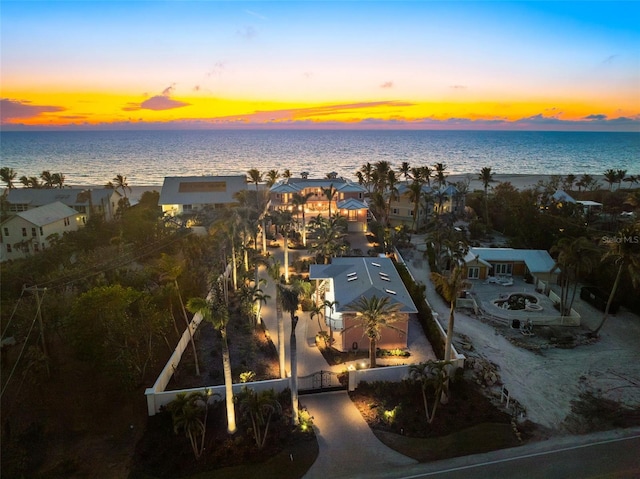 aerial view at dusk featuring a water view and a residential view