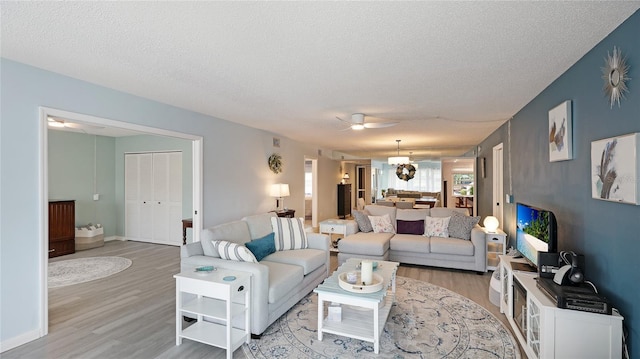 living room with ceiling fan, light hardwood / wood-style flooring, and a textured ceiling